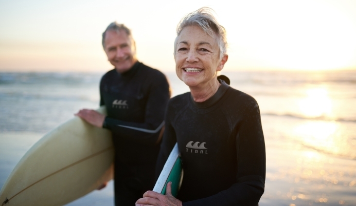 Retirement couple holding surfboards